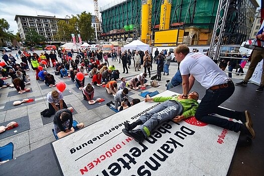 Blick von der Veranstaltungsbühne des es „World Restart a Heart Day“ während des gemeinsamen übens einer Herzmuskelmassage auf sowie vor der Bühne. 